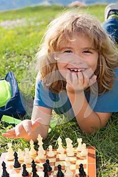 Little kid play chess in park. Child boy playing board game outdoor. Thinking child brainstorming and idea in chess game