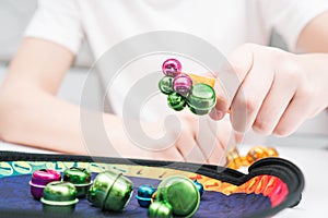 Little kid play toy sitting at table closeup. Hand of child magnetize and pick up colorful metal playthings from plate.