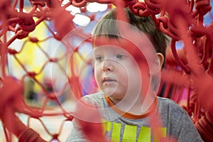 Little kid playing behind the net at indoor playground