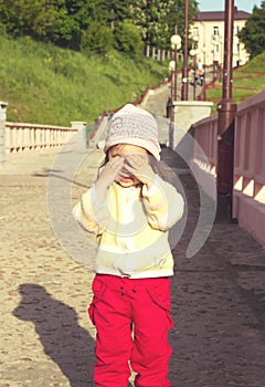 little kid is playing hide-and-seek hiding face. Toned