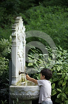 Little kid playing with water from Ottoman style classic fountain