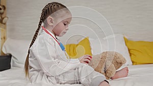 little kid plays with teddy bear sitting on bed in hospital, childhood dream of becoming doctor, kid veterinarian