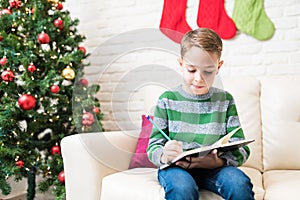 Little Kid Preparing His Wish List At Home In Christmas