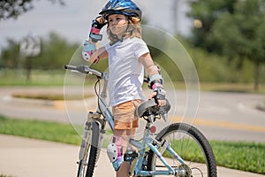 Little kid riding a bike in summer park. Children learning to drive a bicycle on a driveway outside. Kid riding bikes in