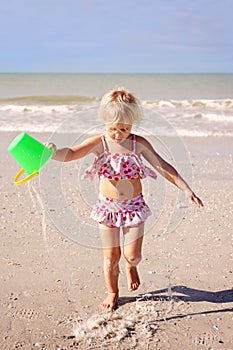 Little Kid Running on The Beach by The Ocean with a Bucket of Water