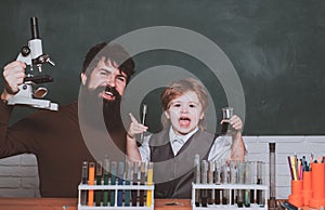 Little kid scientist earning chemistry in school lab. Biology experiments with microscope. Man teaches child. Daddy and