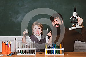 Little kid scientist earning chemistry in school lab. Biology experiments with microscope. Man teaches child. Daddy and