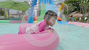 Little kid swimming in pool, relaxing in the swiming pool in a summer hot day. refershing in holiday, a pink float enjoying the