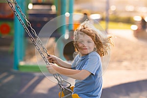 Little kid swinging portrait. Adorable child having fun on a swing on summer day.