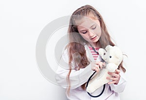 Little kid using Doctor suit and equipment to check Teddy bea