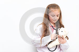 Little kid using Doctor suit and equipment to check Teddy bea