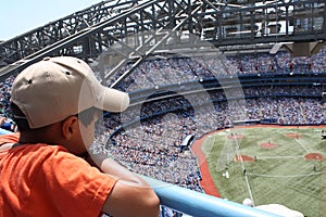 Little kid is watching baseball game on a big stadium