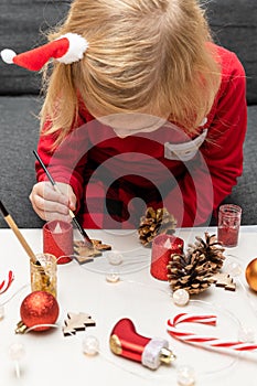 Little kid wearing christmas santa holiday pajamas, doing crafts Christmas tree decorations