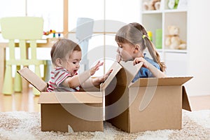 Little kids boy and girl playing in cardboard boxes. Children have fun.