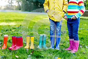 Little kids, boys or girls in jeans and yellow jacket in colorful rain boots