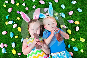 Little kids eating chocolate rabbit on Easter egg hunt