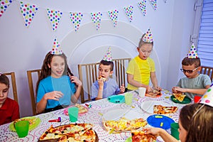 the little kids are eating pizza at the birthday party