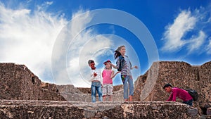 Little kids front shot with white clouds background. Modern children on the ancient fort sight