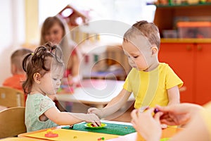 Little kids girl and boy molding from play dough in creche