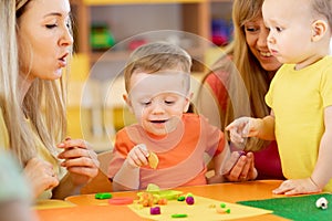 Little kids having fun together with moms. Creative kids molding at home. Children boys play with plasticine or dough.