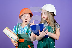 Little kids in helmet with tablet and roller. Labor day. 1 may. small girls repairing together in workshop. Foreman