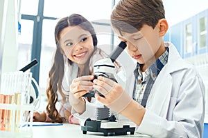 Little kids learning chemistry in school laboratory microscope experiment notes