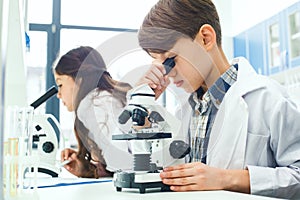 Little kids learning chemistry in school laboratory microscope project