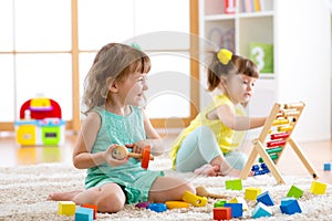 Little kids playing with abacus and constructor toys in kindergarten, playschool or daycare center photo