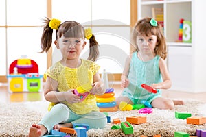 Little kids playing with colorful toys on the floor at home or kindergarten. Educational games for children.