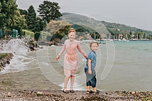 Little kids playing by the lake on a very windy day under summer rain