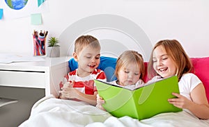 Little kids reading book in bed at home