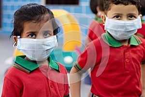 Little kids at school with medical face mask looking at camera - concept School reopen or back to school after covid-19 or coronav