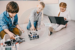 little kids sitting on floor at stem education class with robots