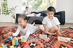 Little kids sitting on the floor with toys and colouring in a book. Small mixed race brother and sister playing together