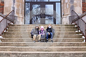 Little Kids Sitting on Steps to School Building with Protective Covid Masks