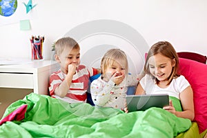 Little kids with tablet pc in bed at home