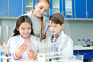 Little kids with teacher in school laboratory experiment