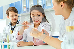 Little kids with teacher in school laboratory making experiment