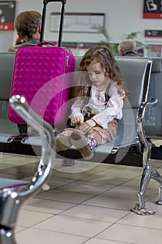 Little kit girl waiting for flight in airport hall