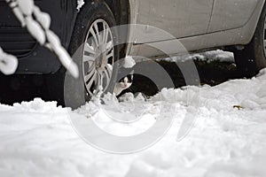 little kitten hidden under the car in the winter in the snow