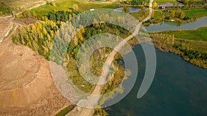 Little lake or pond of unusual shape with a beautiful autumn nature and gravel piles photographed from above with a drone.