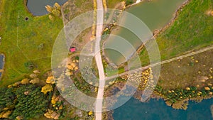 Little lake or pond of unusual shape with a beautiful autumn nature and mud road photographed from above with a drone.