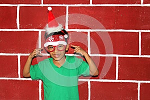 Little Latino boy with Christmas hat and glasses is happy and excited for the arrival of December and Christmas shows his enthusia