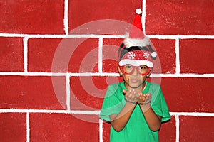 Little Latino boy with Christmas hat and glasses is happy and excited for the arrival of December and Christmas shows his enthusia