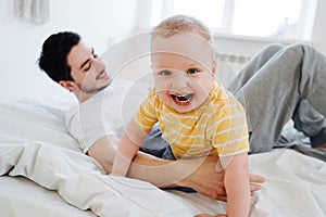 Little laughing boy woke dad up in the bedroom