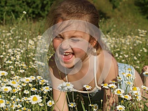 Little girl among the chamomile field and green grass