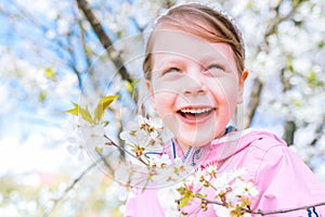 Little laughing girl squinting eyes on a spring background with