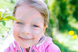 Little laughing girl squinting eyes on a spring background