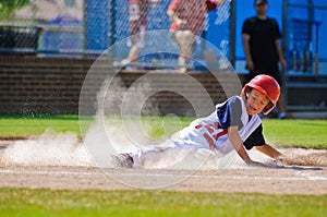 Little league baseball player sliding home.