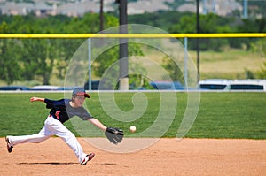 Little league boy reach out to catch ball